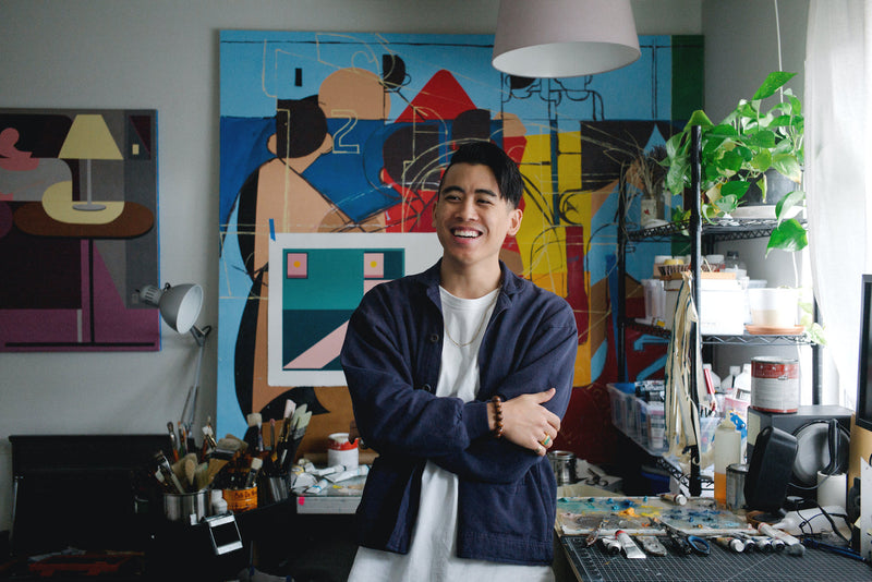 Portrait of artist Adrian Kay Wong in his studio with paintings