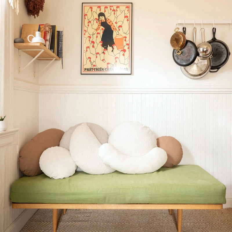 A collection of shaped pillows on a cushioned bench with other decor on the walls
