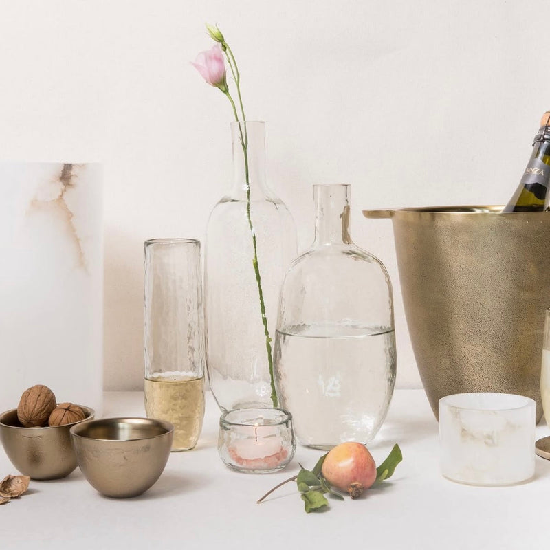 Glass and brass vessels and bottles filled with water, flowers, and nuts