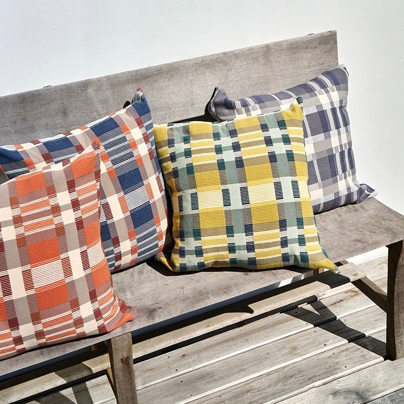 Assortment of plaid pillows in different colors on a wooden bench