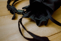 Black drawstring bag with decorative elements closeup on a wooden surface