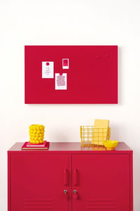 Red locker cabinet with yellow baskets and a red magnetic board on a white wall