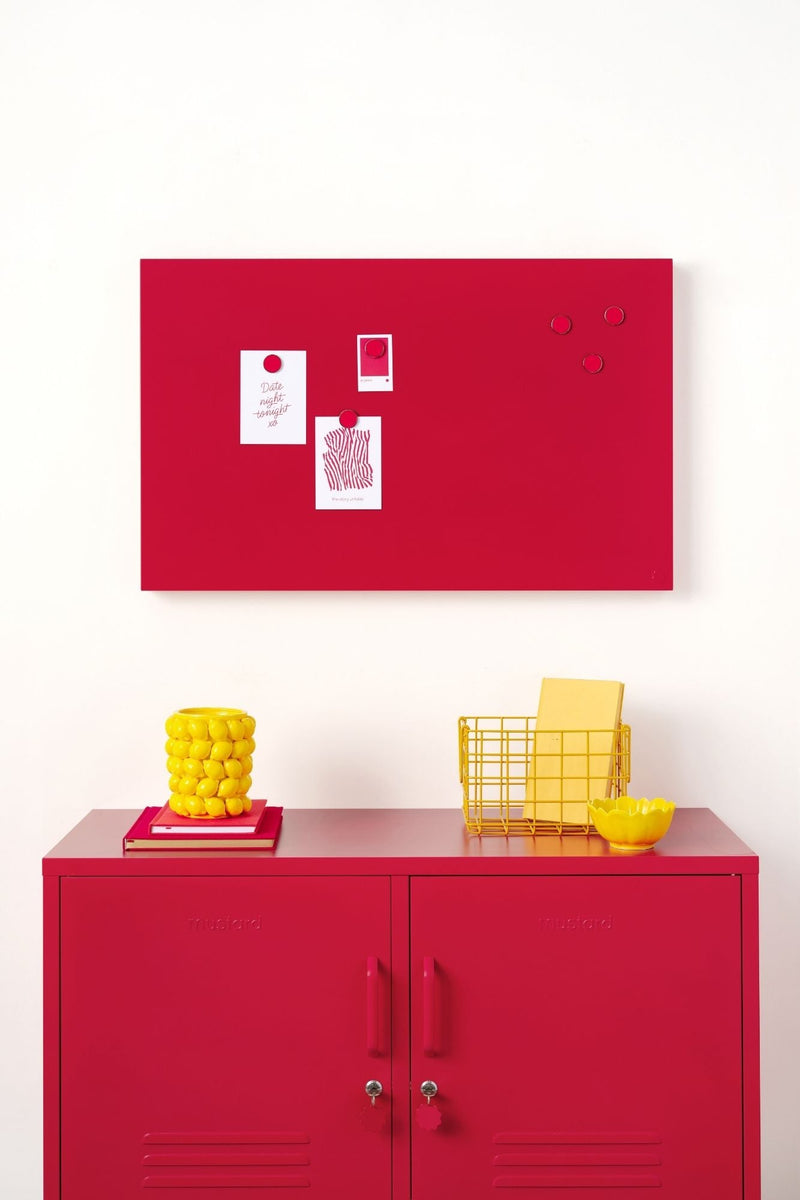 Red locker cabinet with yellow baskets and a red magnetic board on a white wall