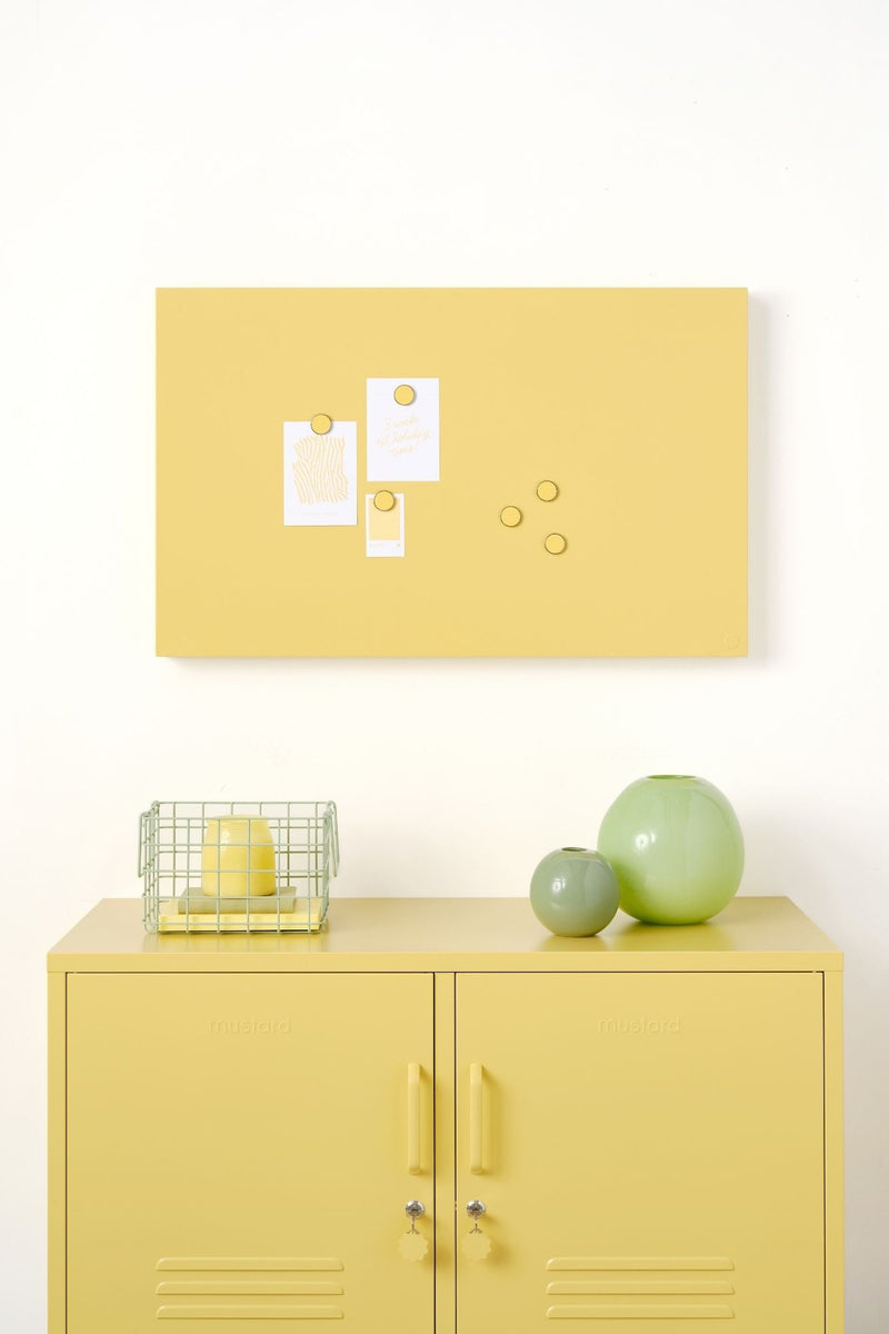 Yellow locker cabinet with magnetic board and decorative items against a white wall