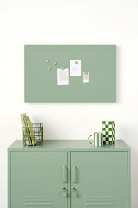 Green magnetic display board with magnets above a green locker.