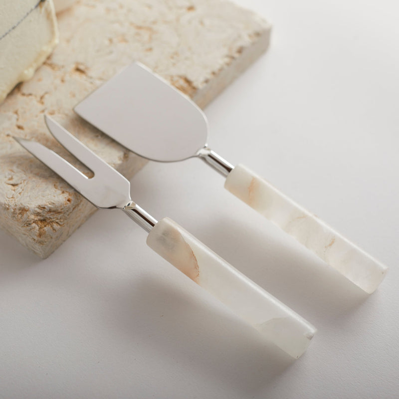 Set of alabaster-handled cheese tools and board on a light background
