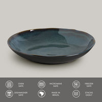 Teal ceramic pasta plate on a gray background with safety and feature icons at the bottom.