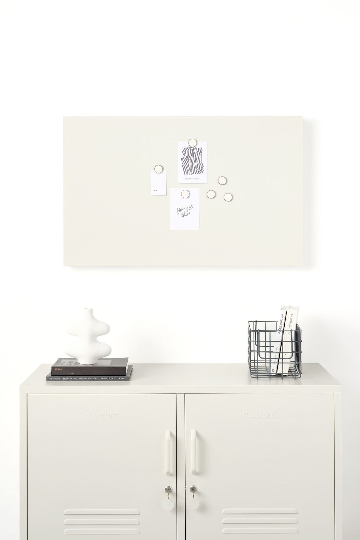 White locker-style cabinet with a basket, and decorative items under a white magnetic display board on a white background