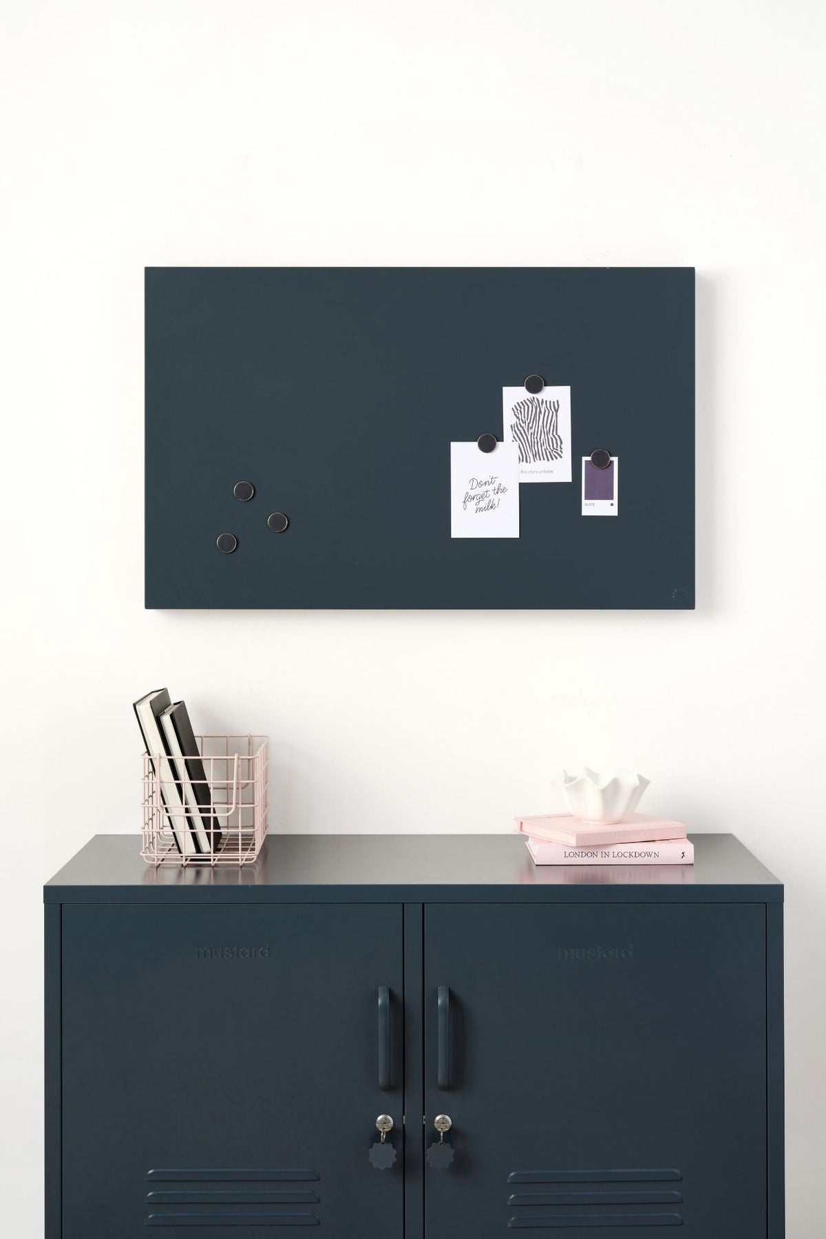 Slate magnetic board on a white wall above a slate locker cabinet with decorative objects