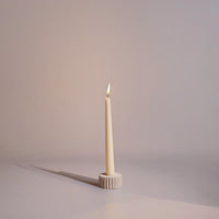 Taper candle in a decorative holder on a plain background