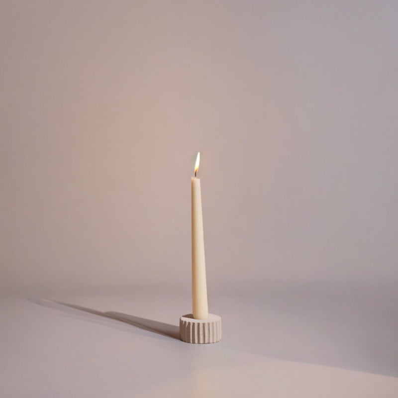 Taper candle in a decorative holder on a plain background