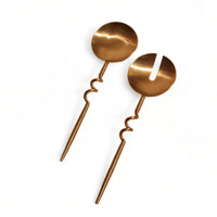Pair of gold serving spoons on a white background