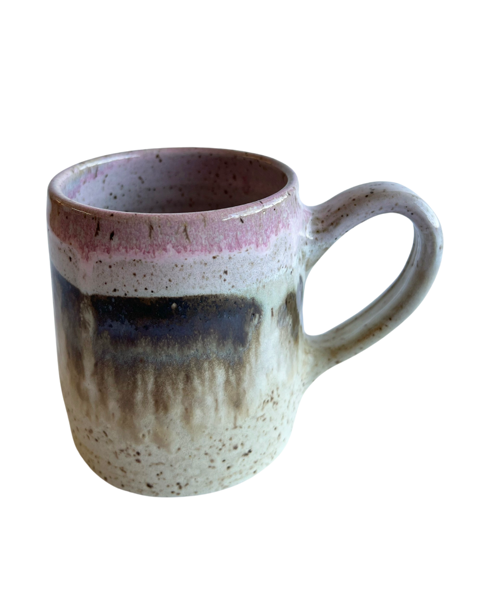 Ceramic mug with light and dark neutral and pink glaze details on a white background