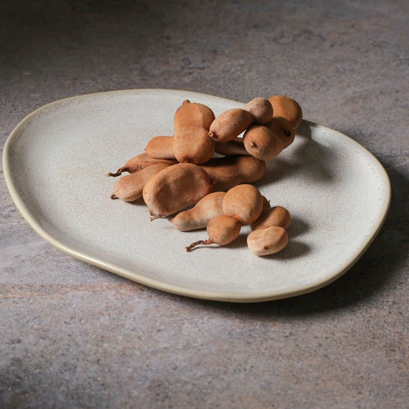 Nuts on an off white plate on a concrete surface