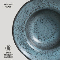 Blue ceramic bowl with speckled texture on a light gray background