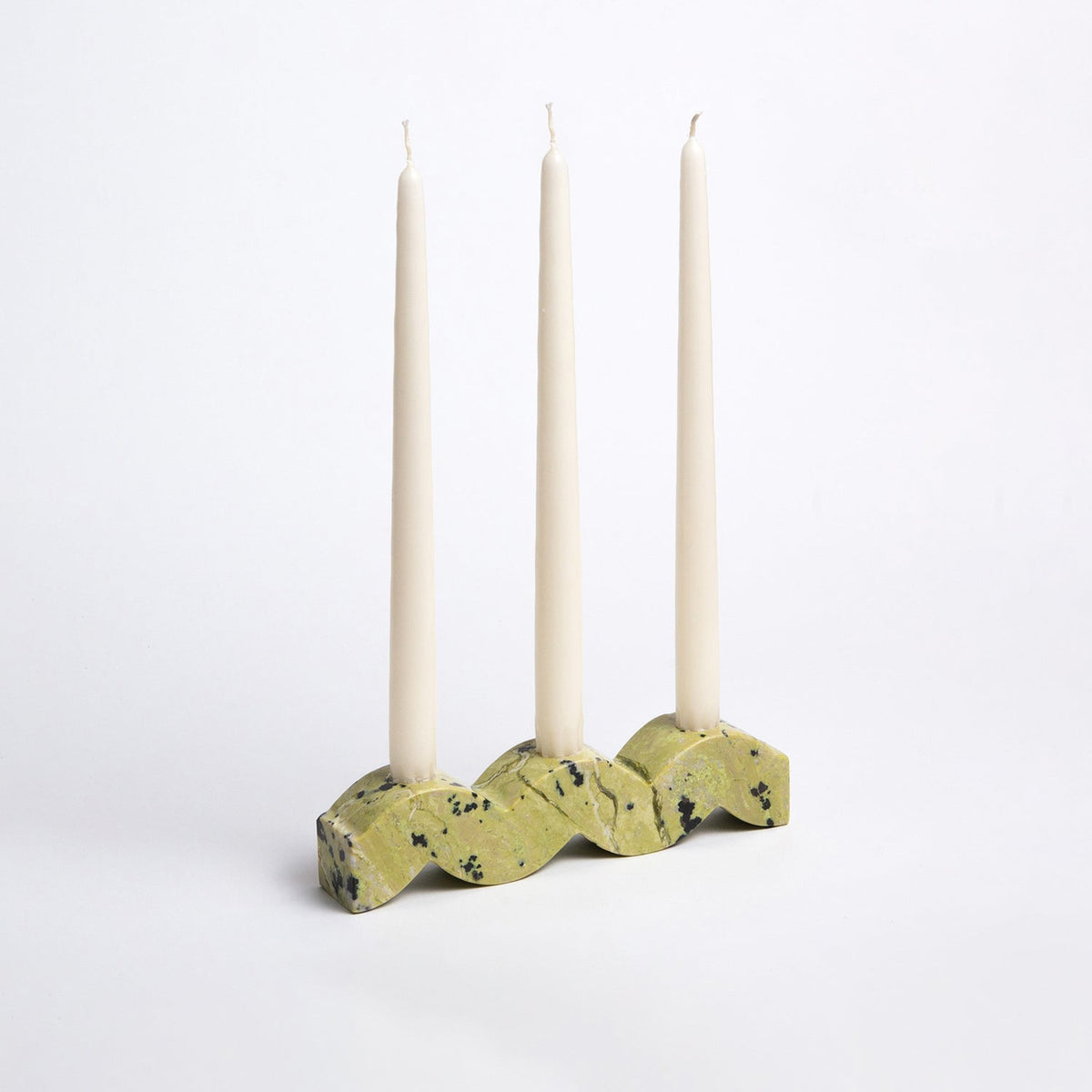 Decorative candle holder with three taper candles on a white background