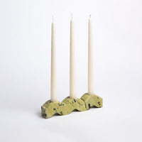 Decorative candle holder with three taper candles on a white background
