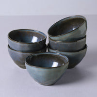 Set of six blue ceramic bowls stacked on a light gray background