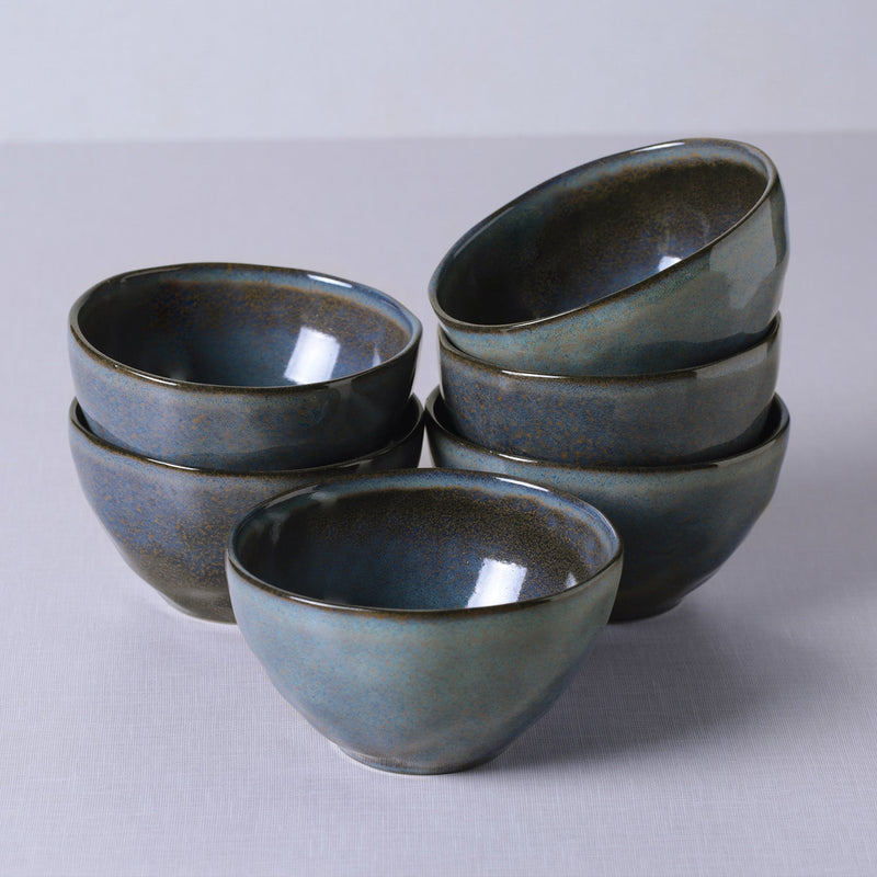 Set of six blue ceramic bowls stacked on a light gray background