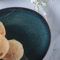 Blue ceramic bowl with pastries on a white surface