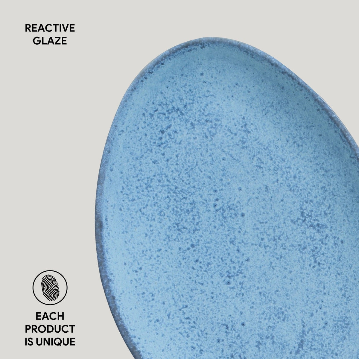 Close-up of a blue ceramic plate with reactive glaze on a gray background