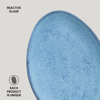 Close-up of a blue ceramic plate with reactive glaze on a gray background