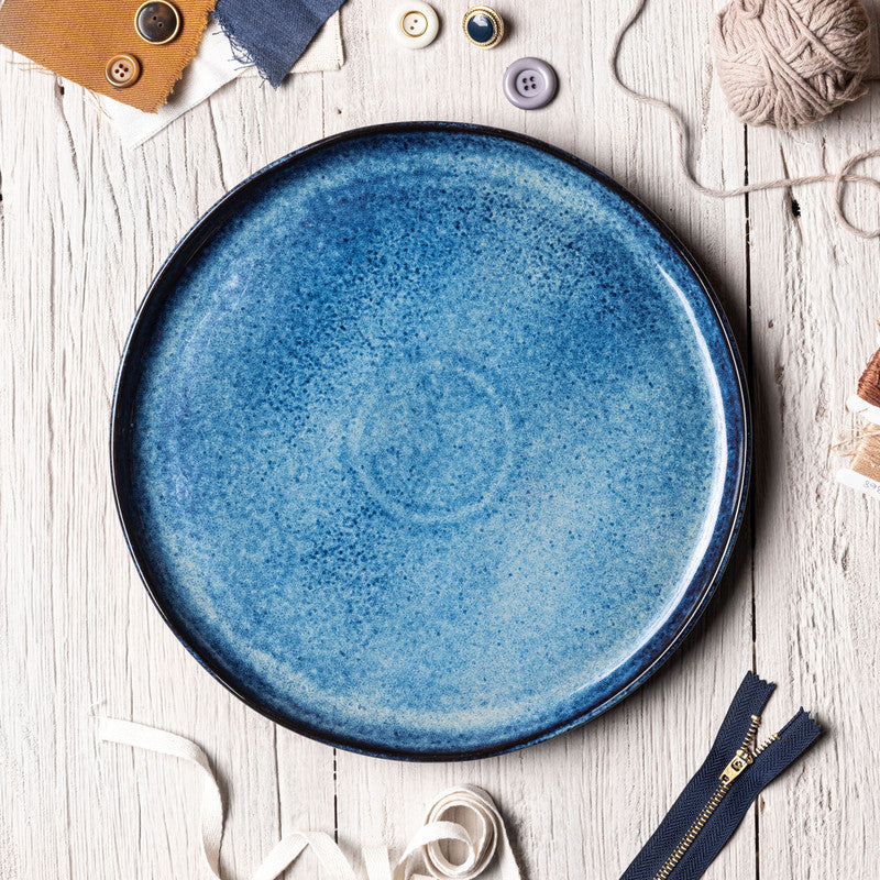 Blue ceramic plate on a wooden surface with decorative trim items.