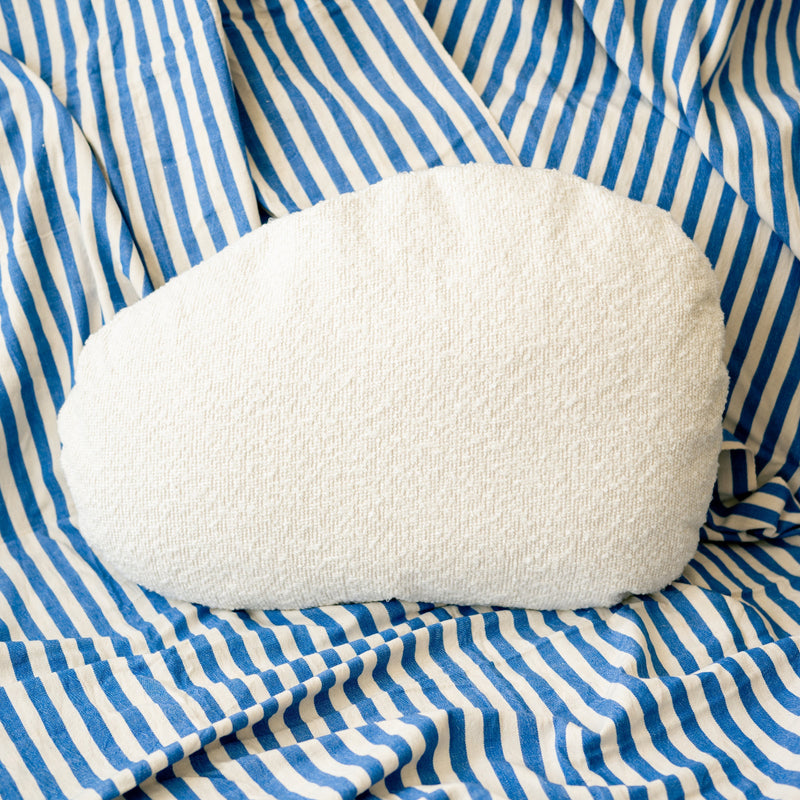 White pillow on a blue and white striped fabric background