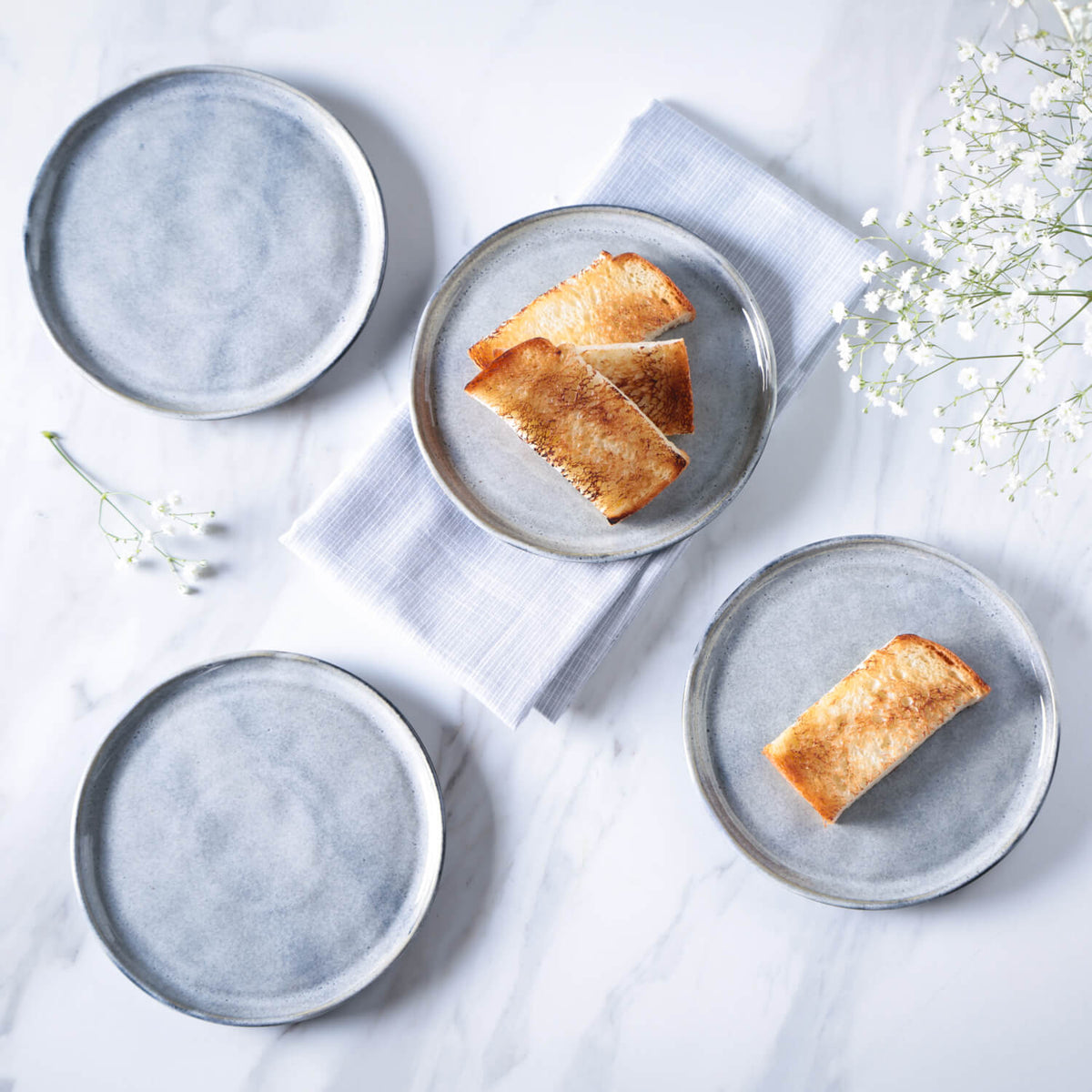 Four round ceramic plates with bread slices on a light background
