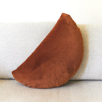 Brown crescent-shaped pillow on a light gray sofa