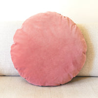 Round pink cushion on a beige sofa