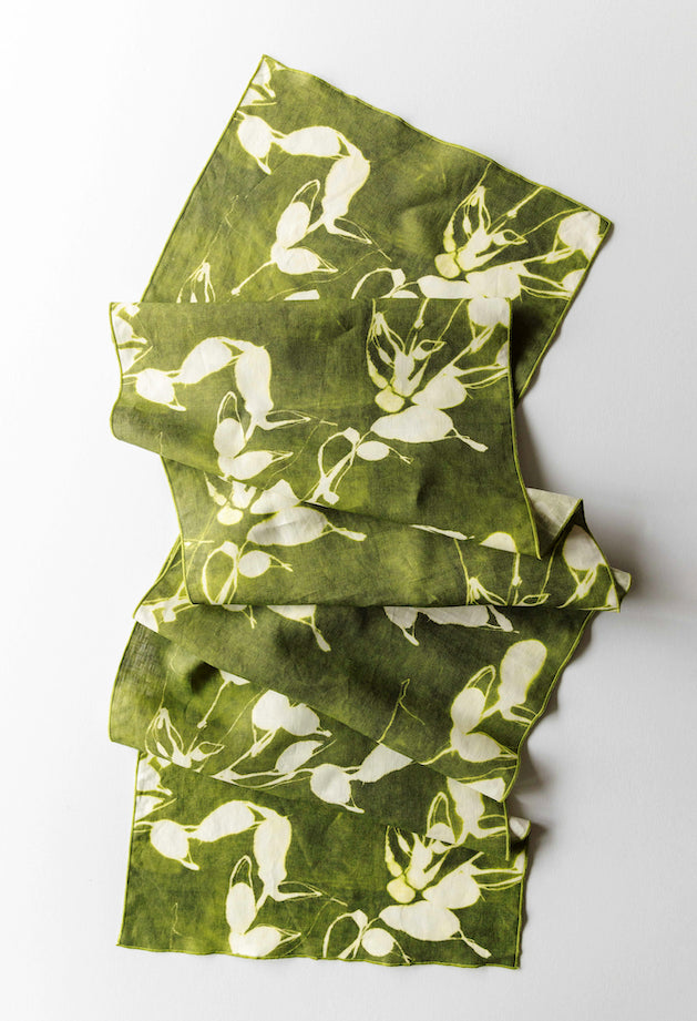 Green folded table runner with a white floral pattern on a white background