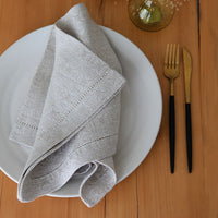 Beige napkin on a white plate with gold and black cutlery on a wooden table