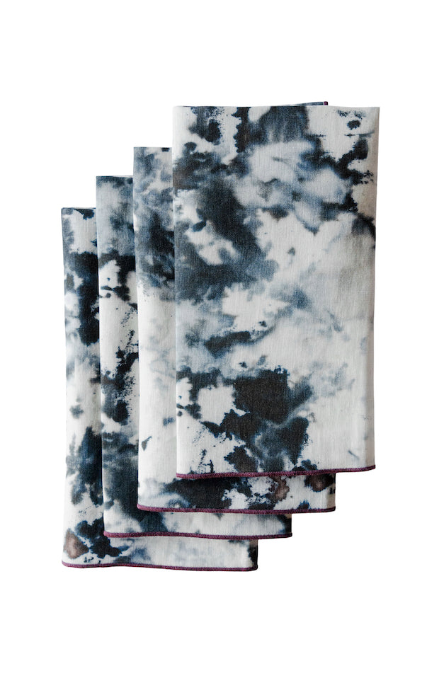 Set of four tie-dye napkins with black and white pattern on a white background