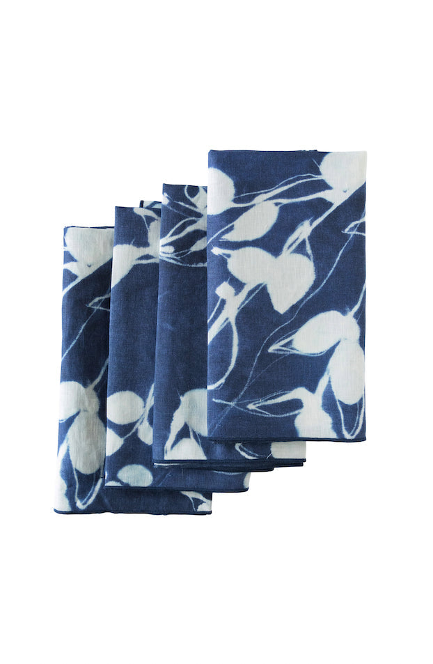 Set of four blue napkins with white floral pattern on a white background