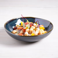 Salad with chickpeas and vegetables in a dark blue bowl on a light background