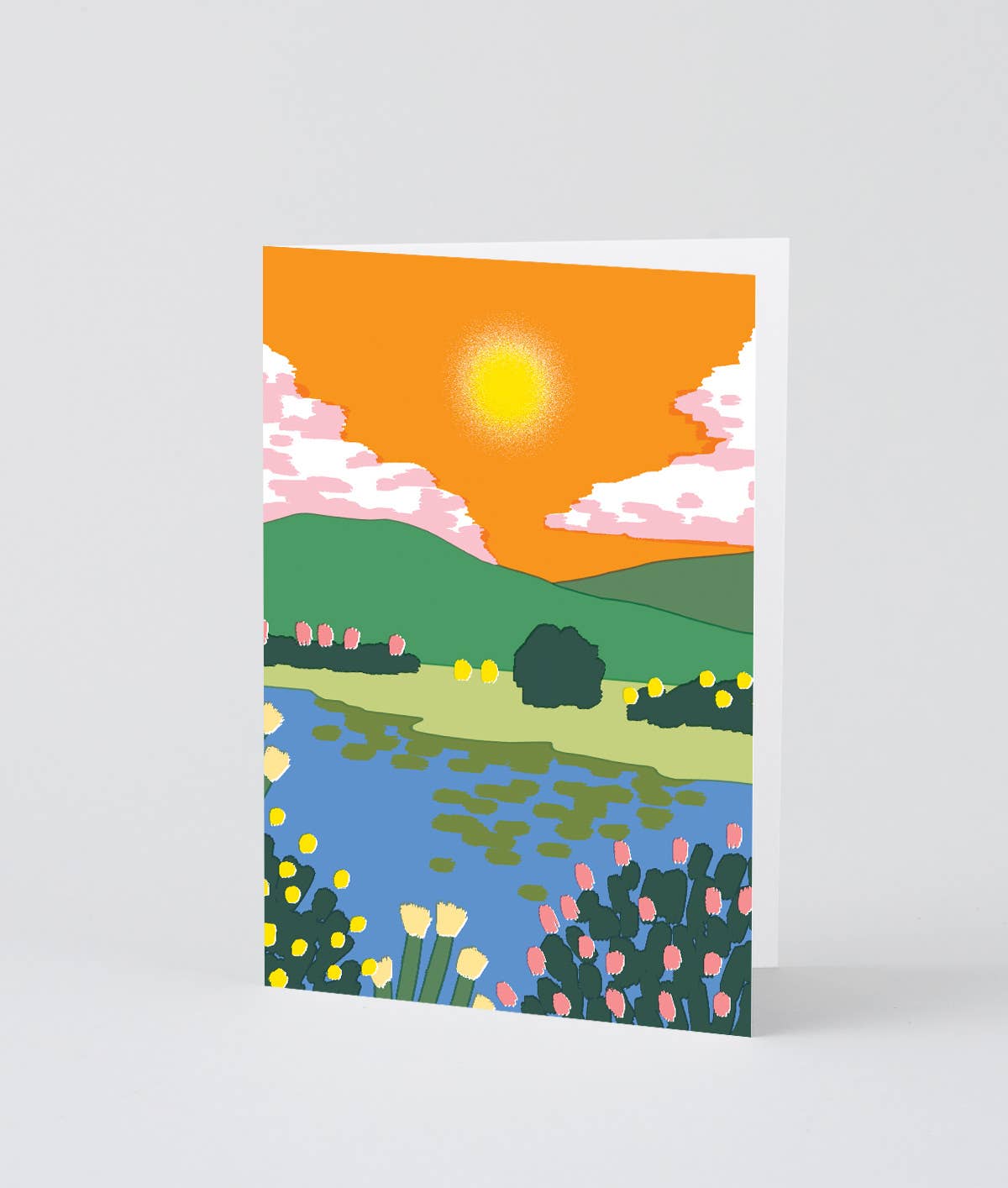 Greeting card with a colorful landscape design featuring a sunset over a lake and flowers.