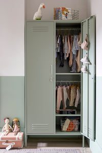 Green wardrobe with clothes and toys in a room.