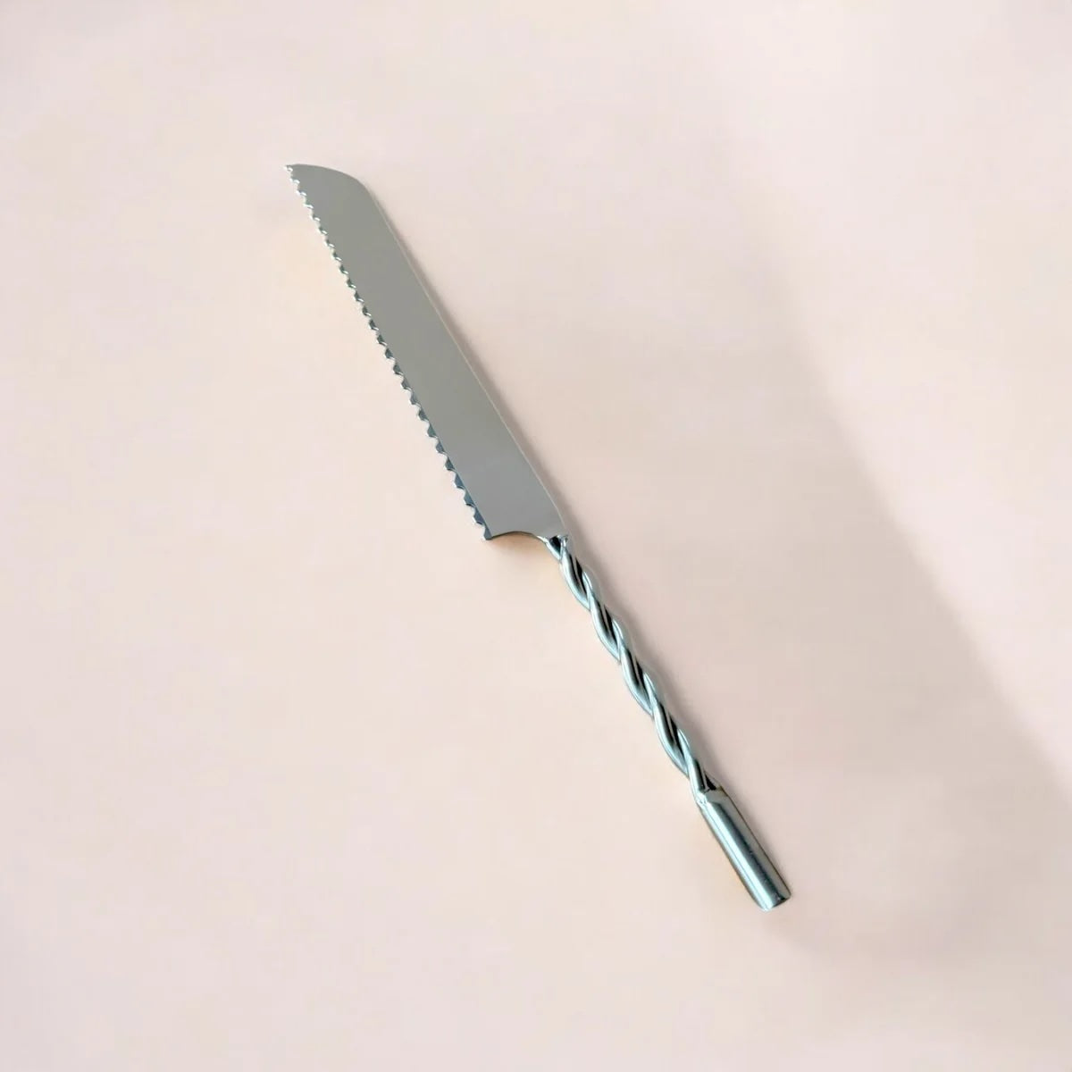 Bread knife with a twisted blade on a beige background