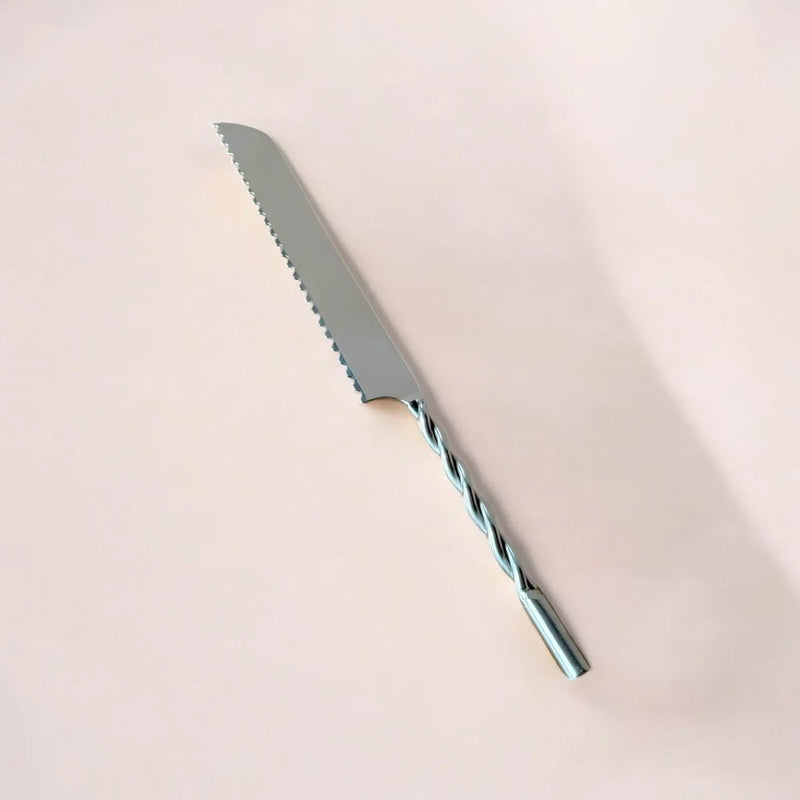 Bread knife with a twisted blade on a beige background