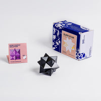 Black geometric puzzle with packaging and solution guide on a white background