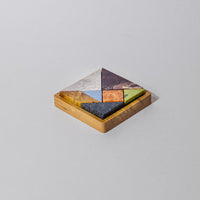 Wooden puzzle with geometric stone pieces on a light gray background
