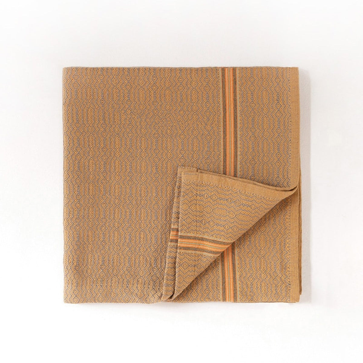Folded cumin colored towel with a subtle pattern on a white background