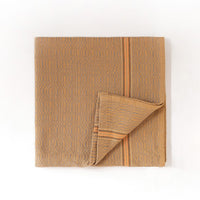 Folded cumin colored towel with a subtle pattern on a white background