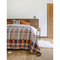 Bed with plaid comforter and pillows in a bedroom setting