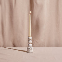 Candle in a terrazzo-patterned candle holder against a beige curtain background