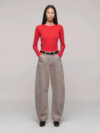 Person wearing a red top and beige pants on a plain background