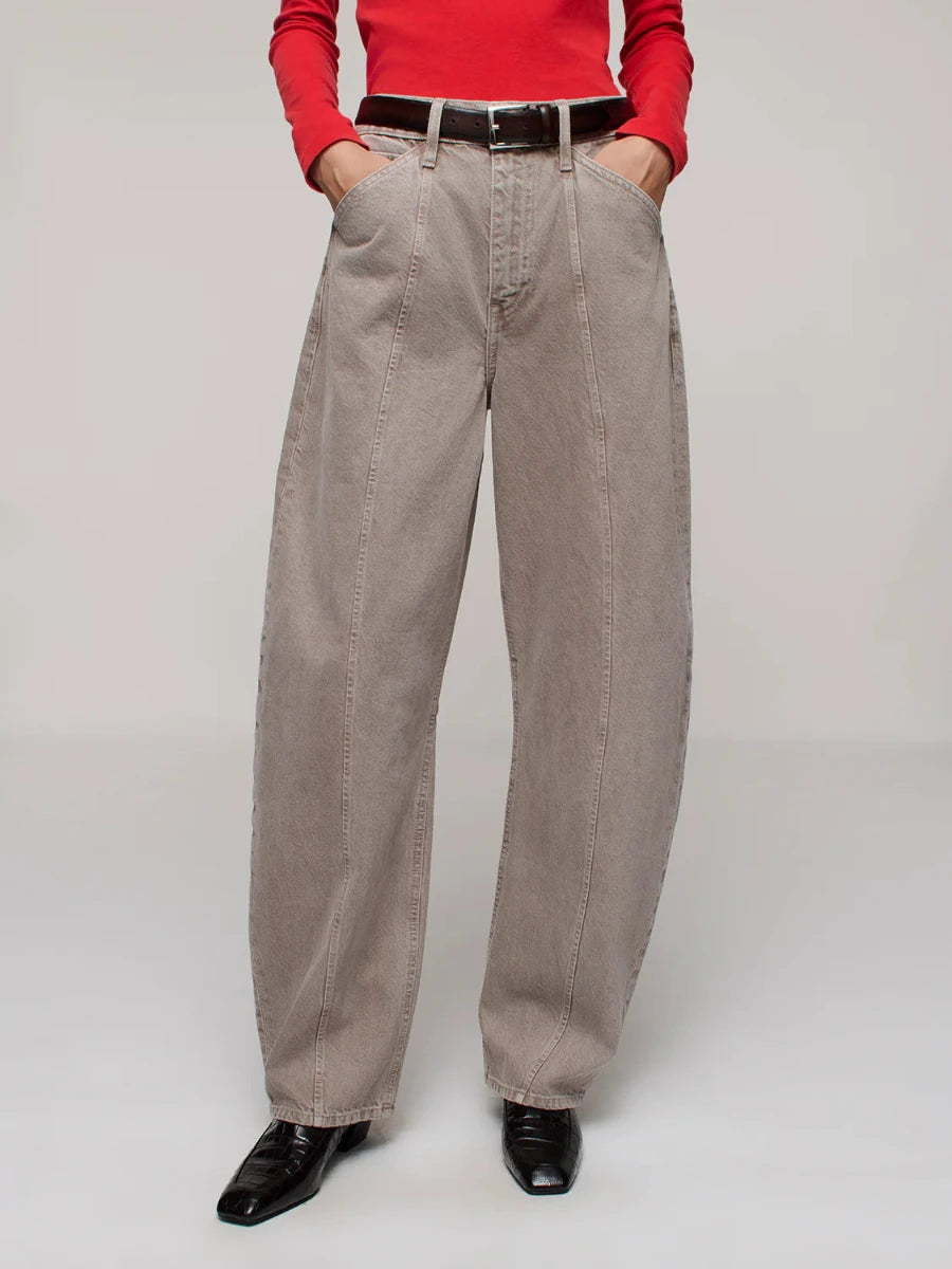 Person wearing beige jeans with a red top on a plain background