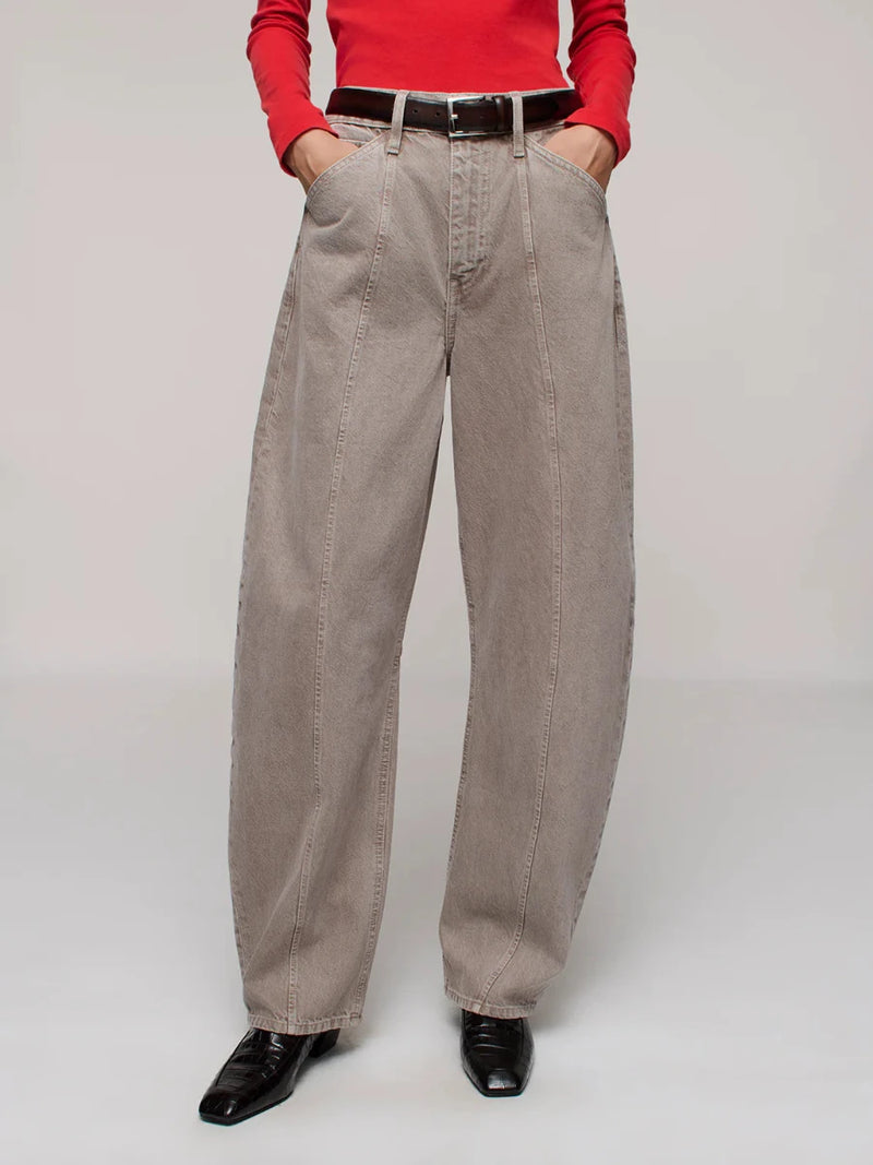 Person wearing beige jeans with a red top on a plain background