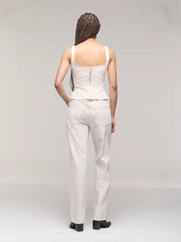 Person wearing a white sleeveless top and pants on a plain background